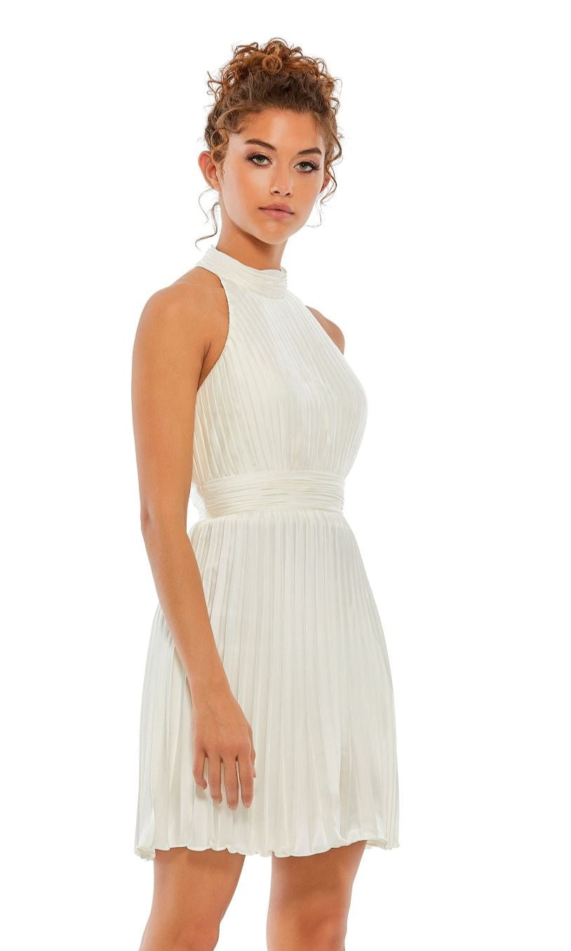 A woman with curly hair wears the Mac Duggal 26645 Short Pleated Hoco Dress, standing against a plain white background.